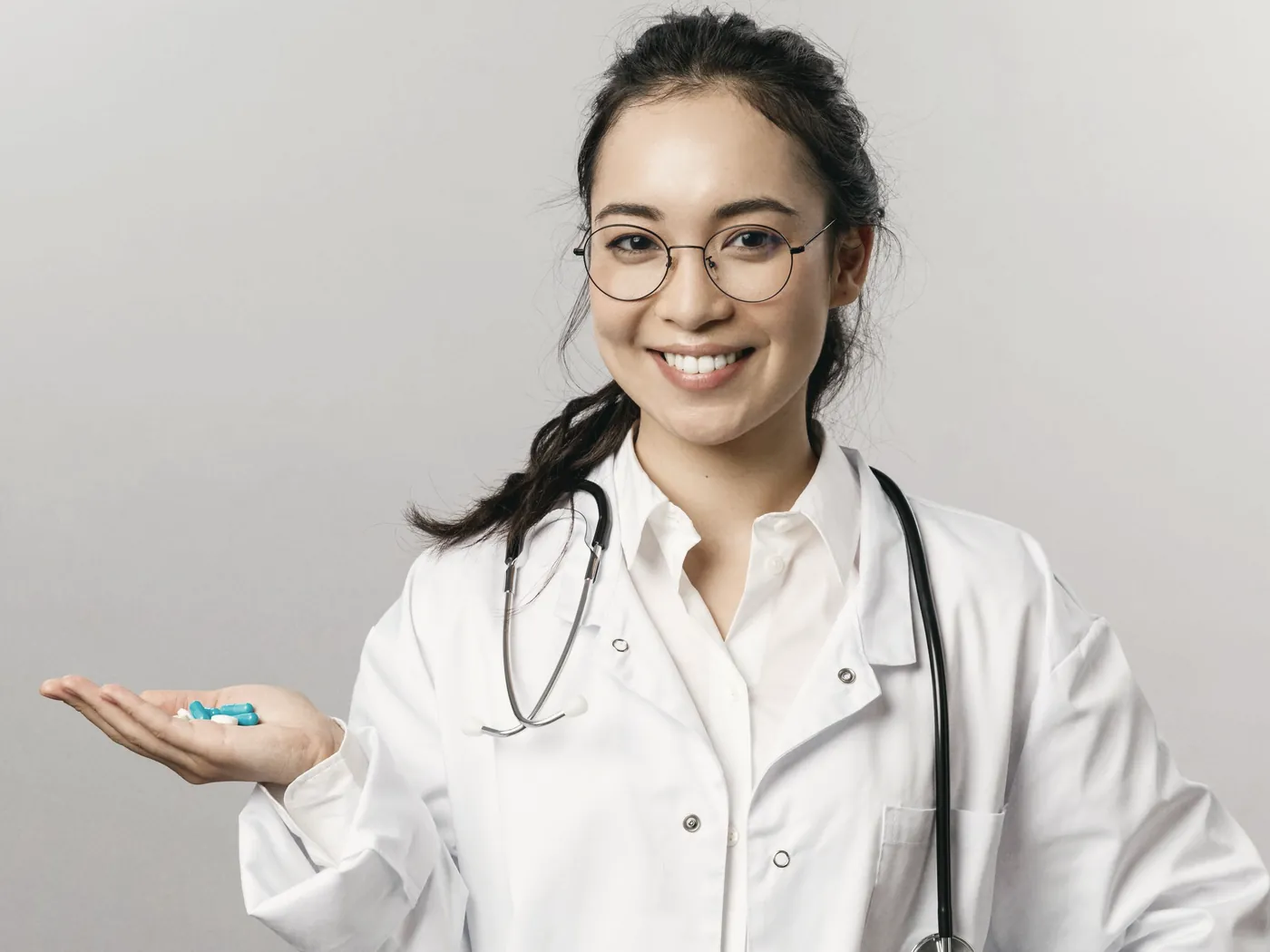 A smiling doctor holding blue tablets in her hand