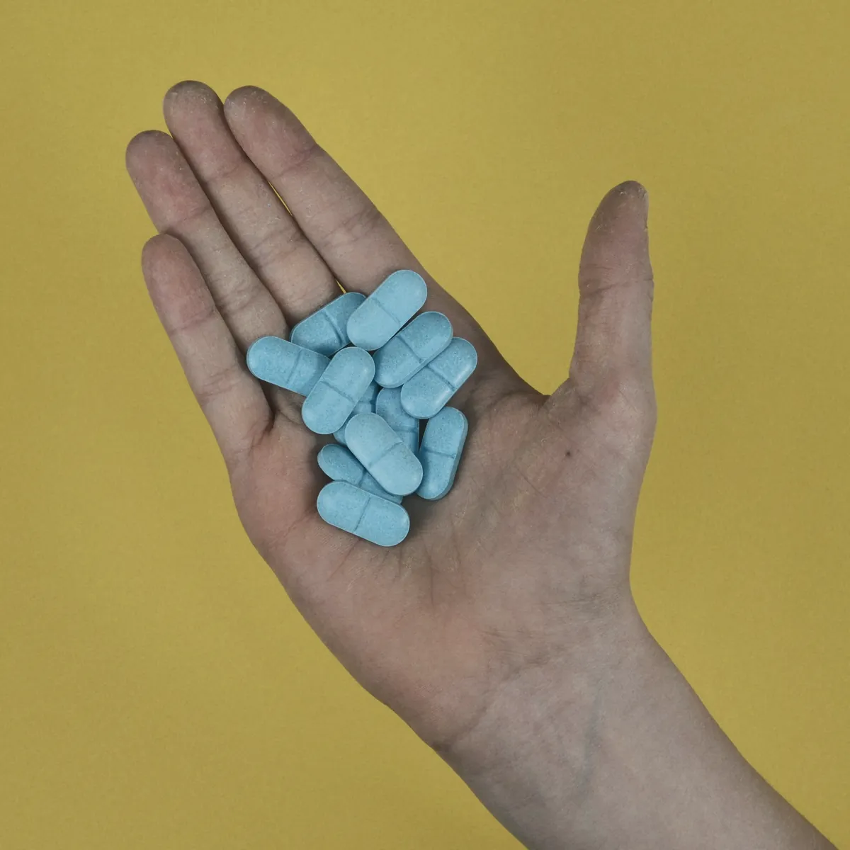 Blue oblong tablets in an open palm