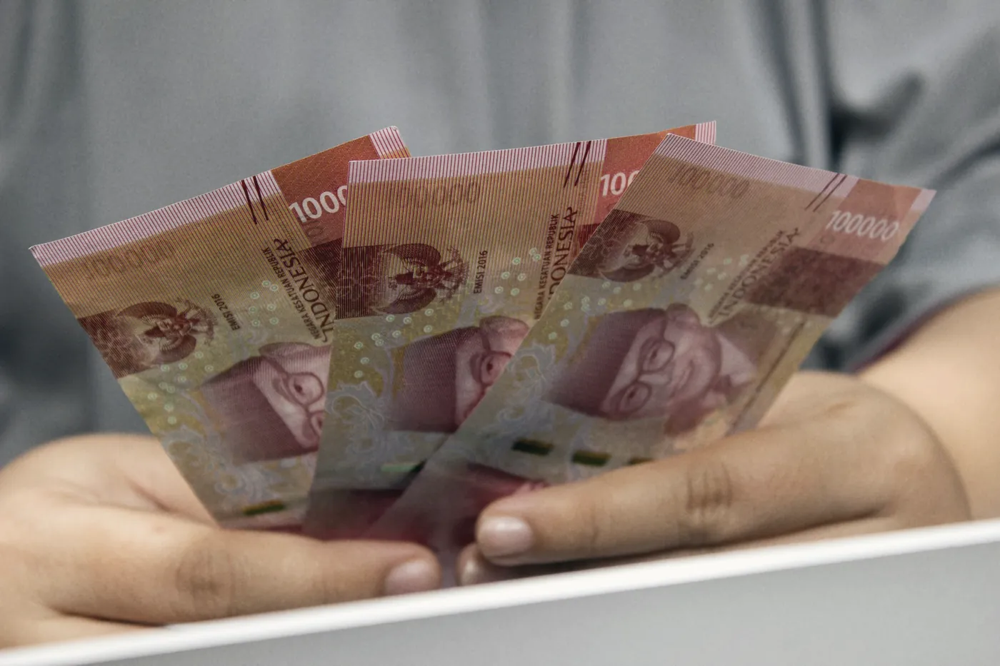 A hand fanning out red banknotes