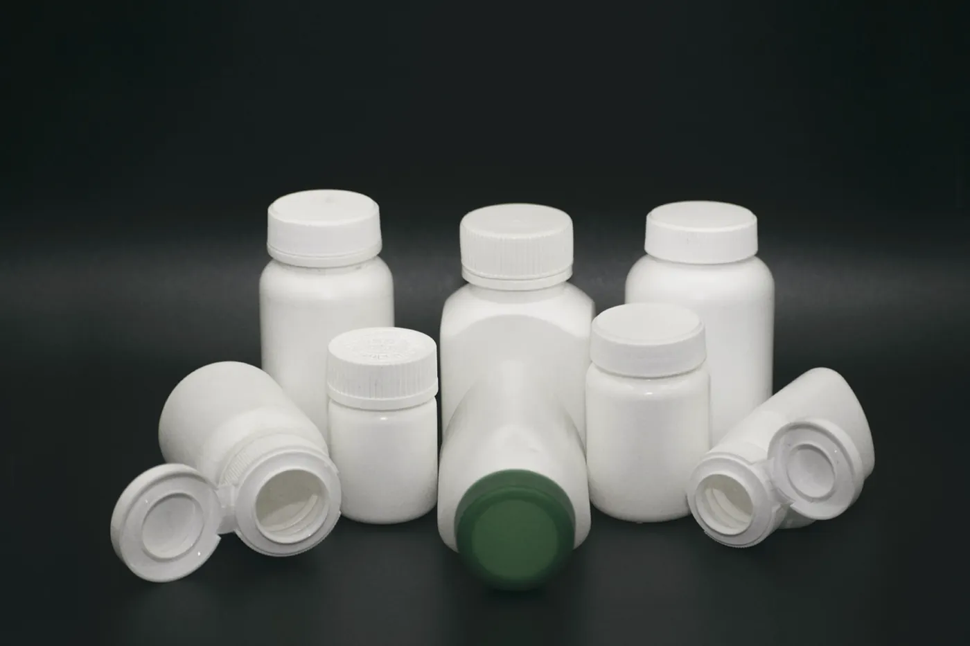 A group of white plastic medicine bottles on a black background