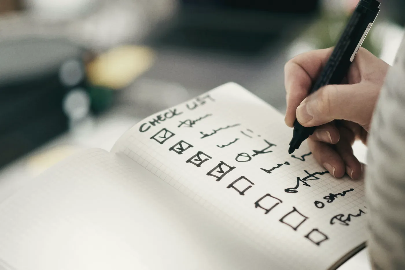 A hand ticking boxes on a handwritten checklist