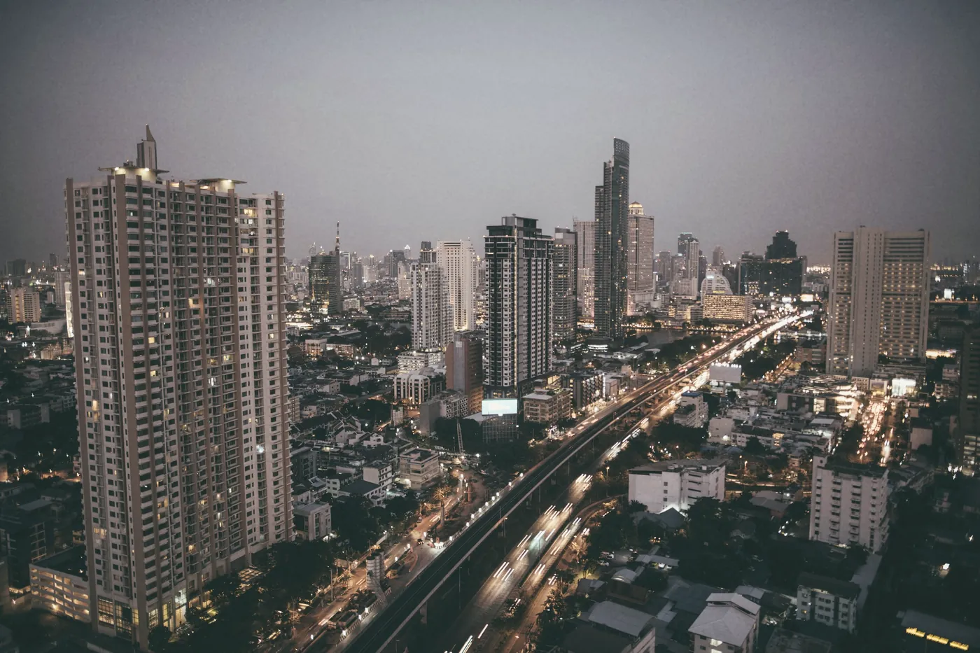 Bangkok high-rise towers and a busy road at dusk