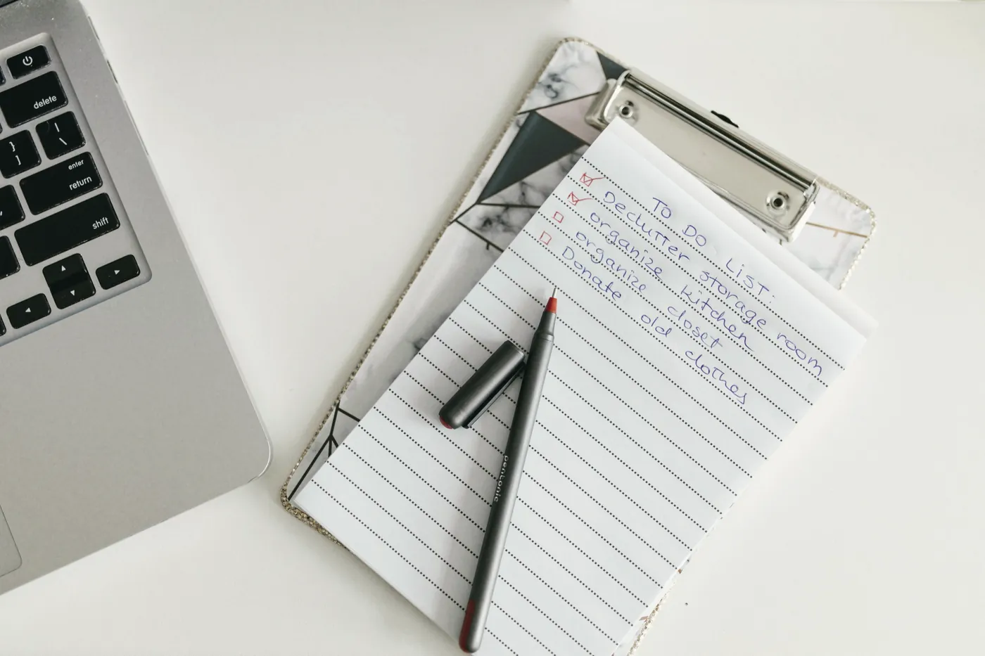 A clipboard with a handwritten list next to a laptop