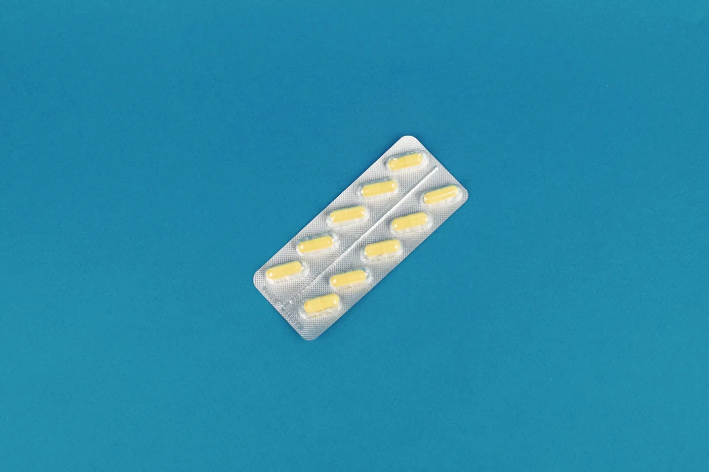 A blister pack of yellow tablets on a bright blue background