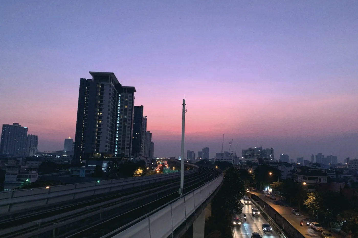 An elevated Bangkok Skytrain line under a purple evening sky