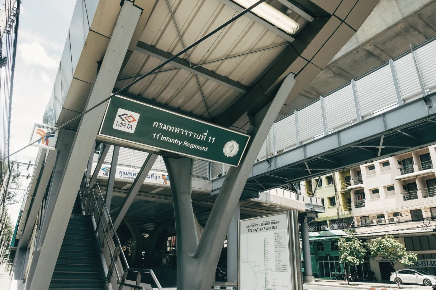 The entrance to a Bangkok rail station with a green sign