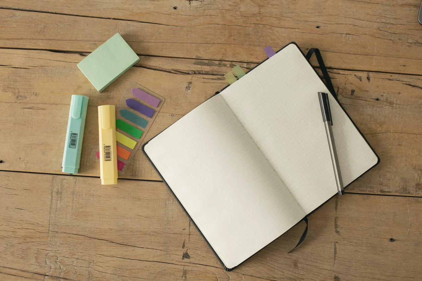 An open notebook with colourful sticky notes and a pen on a wooden table