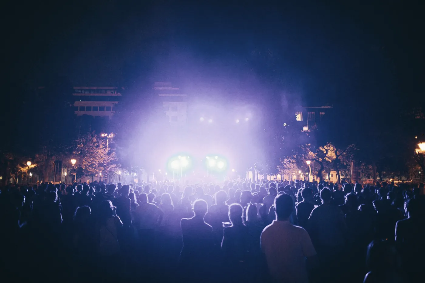 A crowd facing a brightly lit stage at a night concert