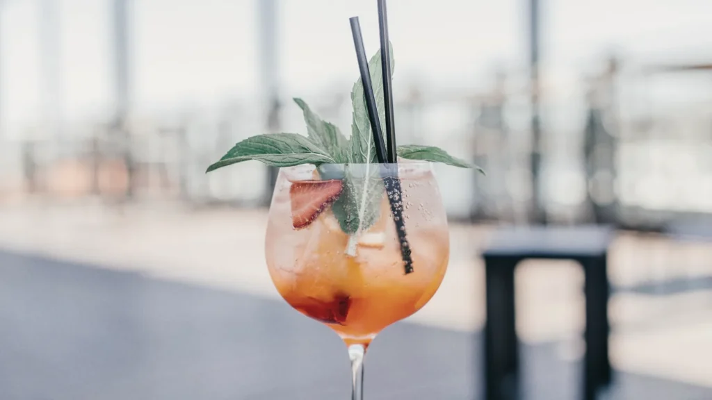 An orange cocktail on a table overlooking the water