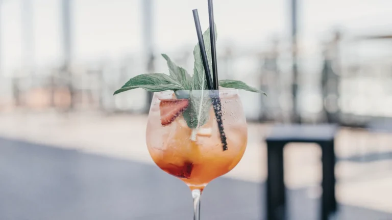An orange cocktail on a table overlooking the water