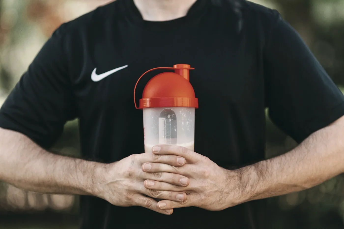 A person holding a protein shaker bottle in both hands