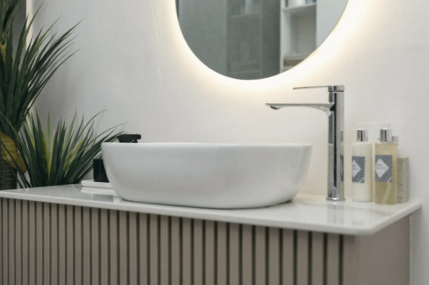 A bright bathroom with a round mirror and a basin