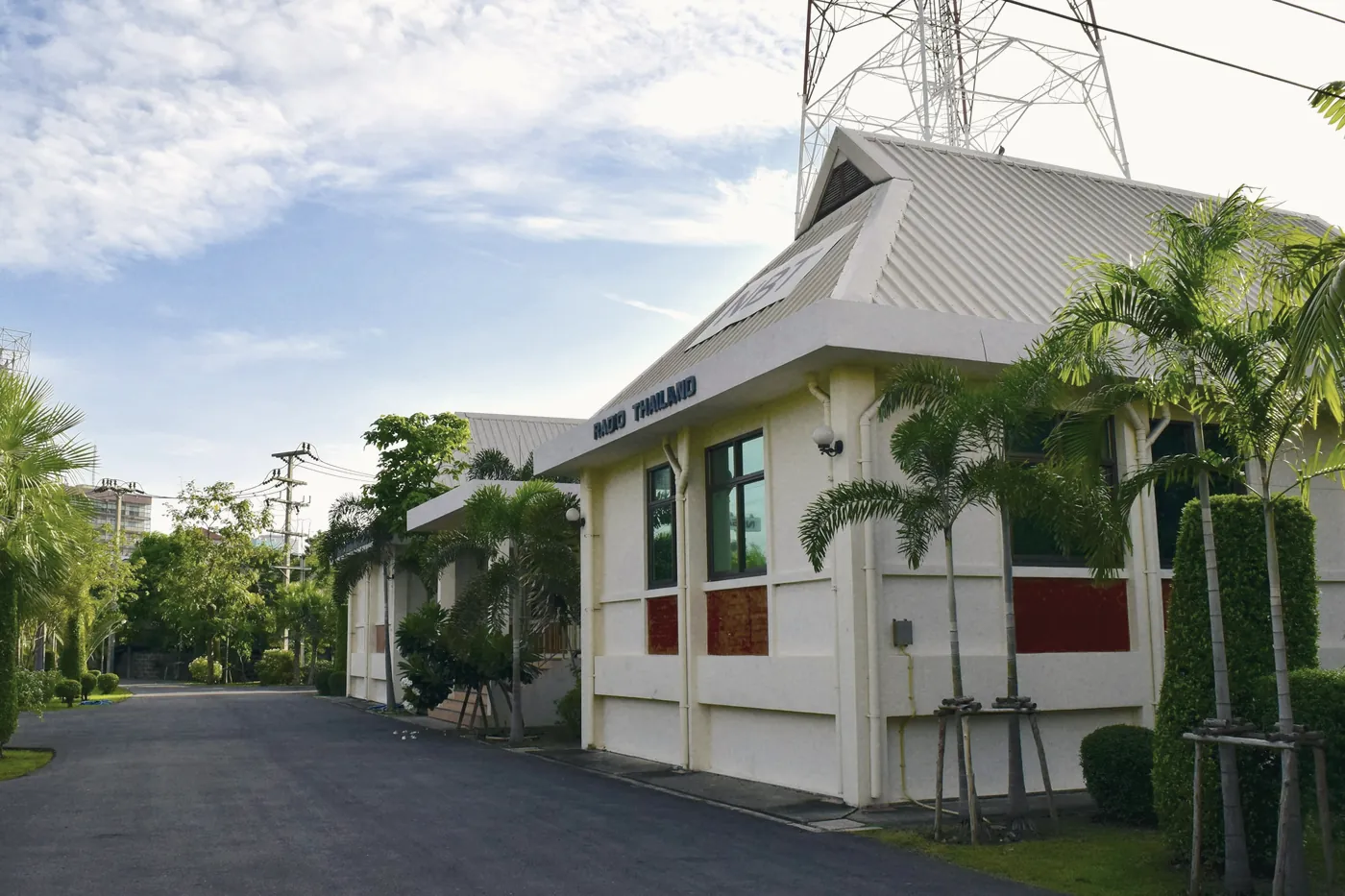 A small white building with a driveway and trees