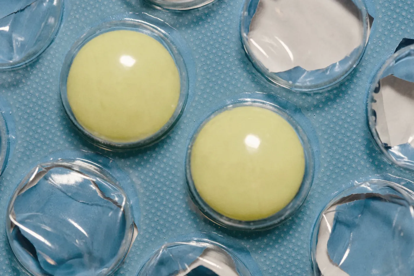 Yellow condoms in clear wrappers on a blue background
