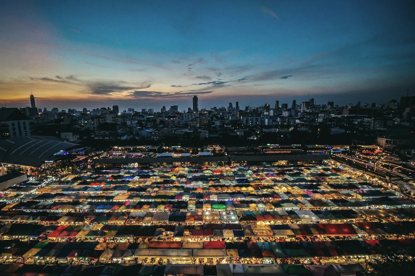 Colourful stalls of a Bangkok night market seen from above at dusk