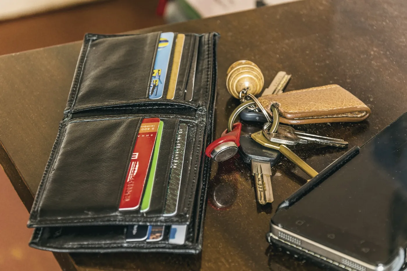A leather wallet with cards and a set of keys on a table