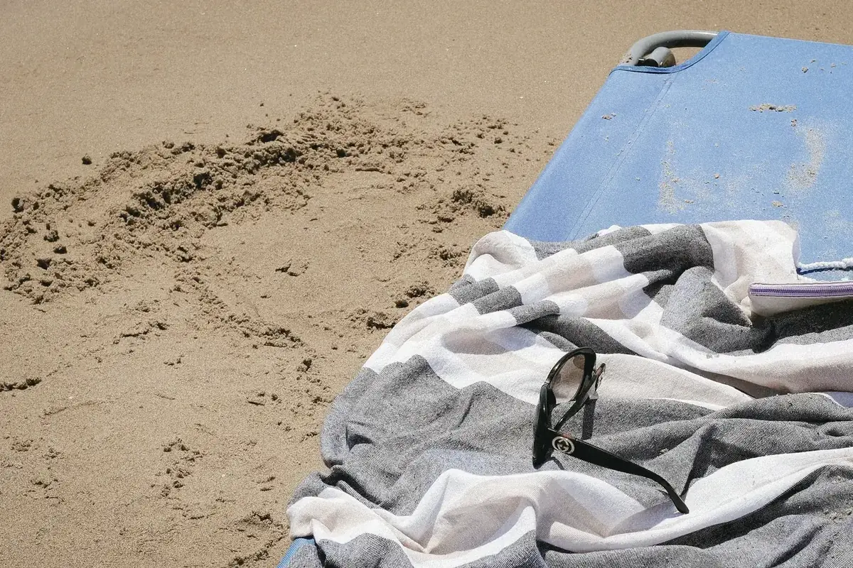 A beach towel with a phone lying on the sand