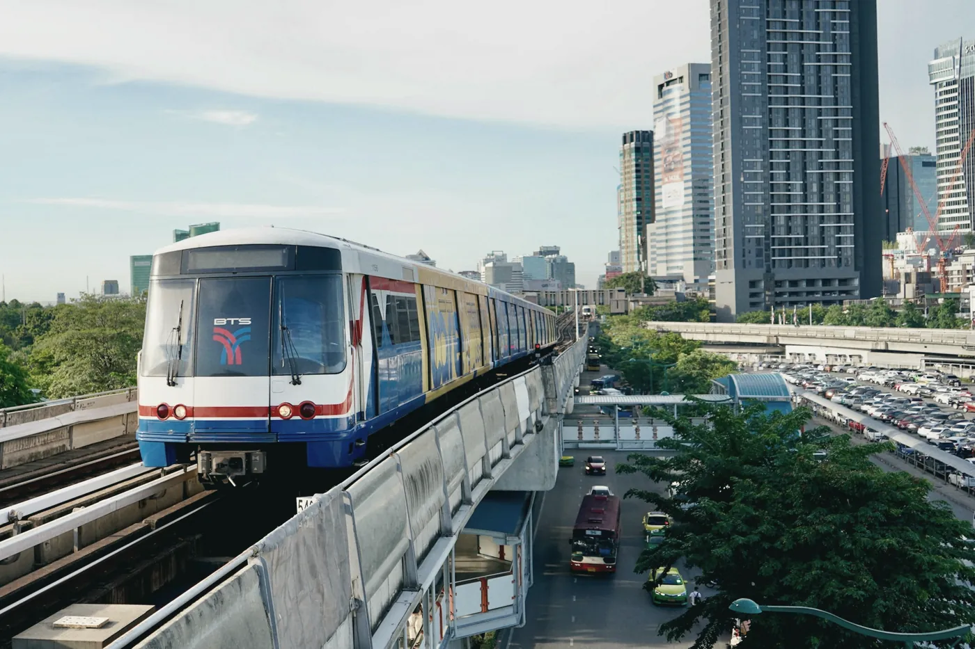 A BTS Skytrain on an elevated track between Bangkok office towers