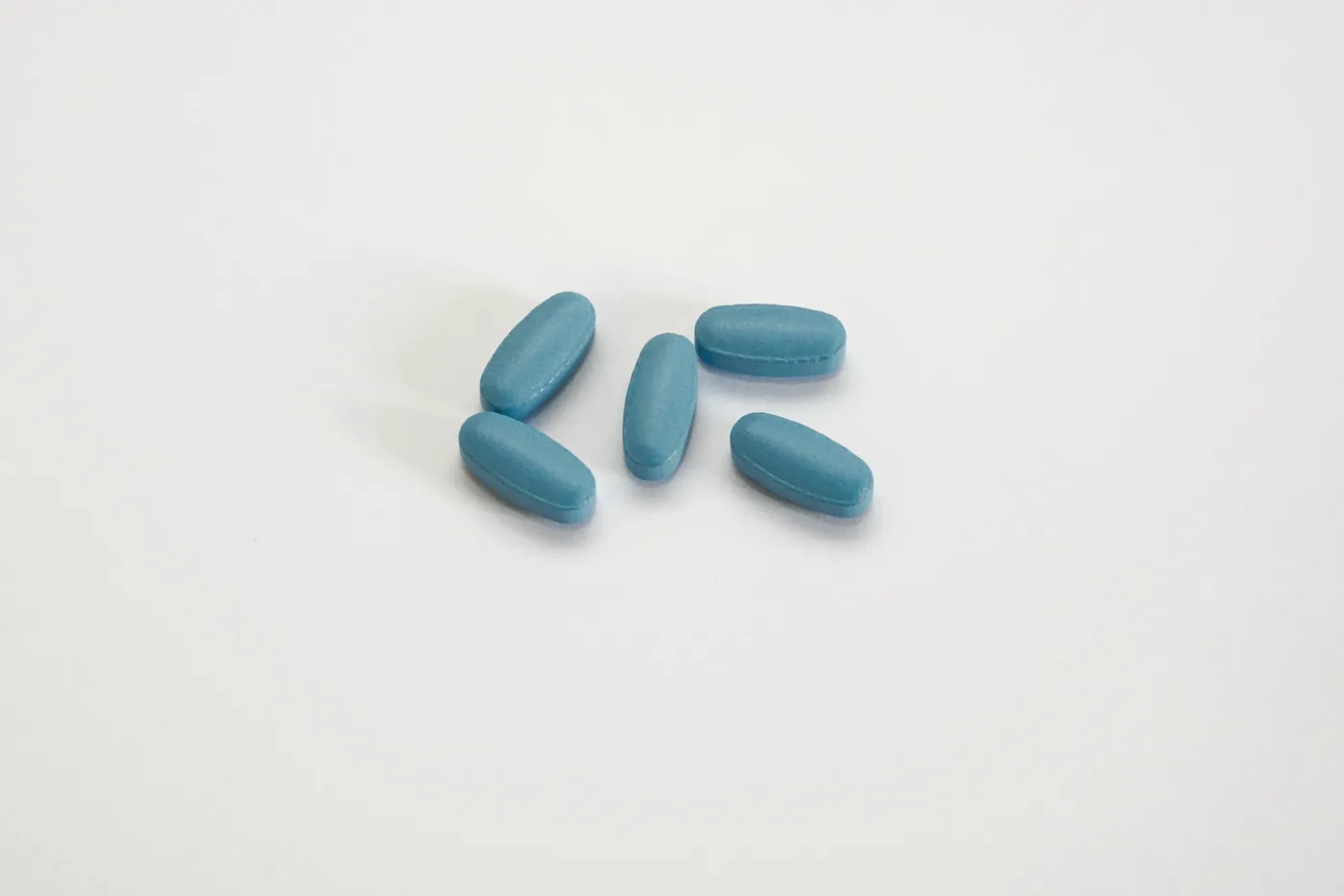 Four blue oblong tablets on a plain white surface