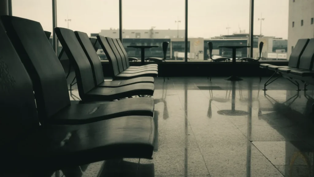 Rows of empty seats in an airport departure lounge beside large windows