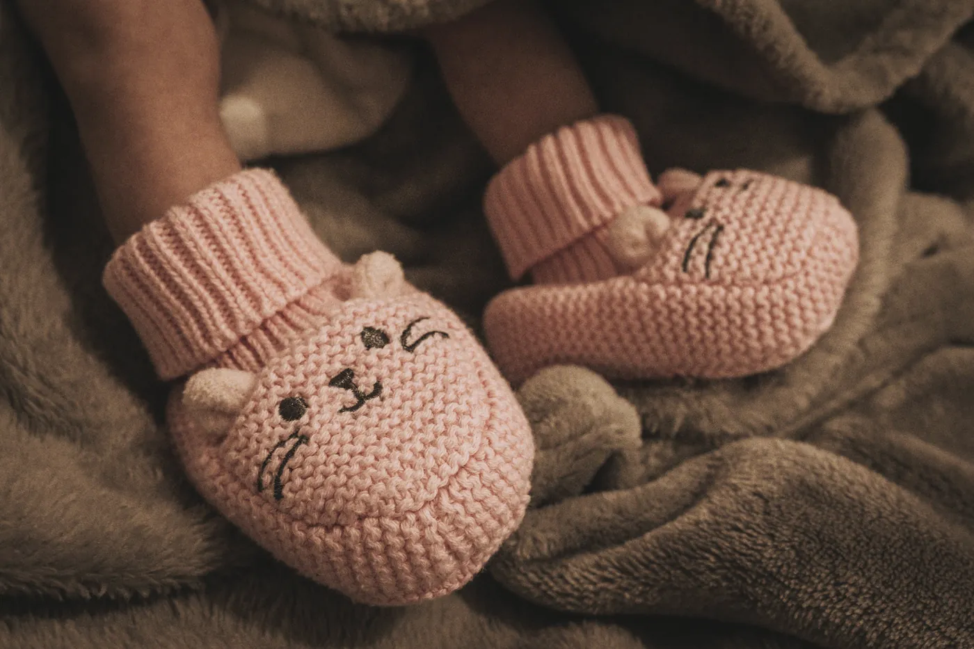 Knitted baby booties resting on a soft blanket