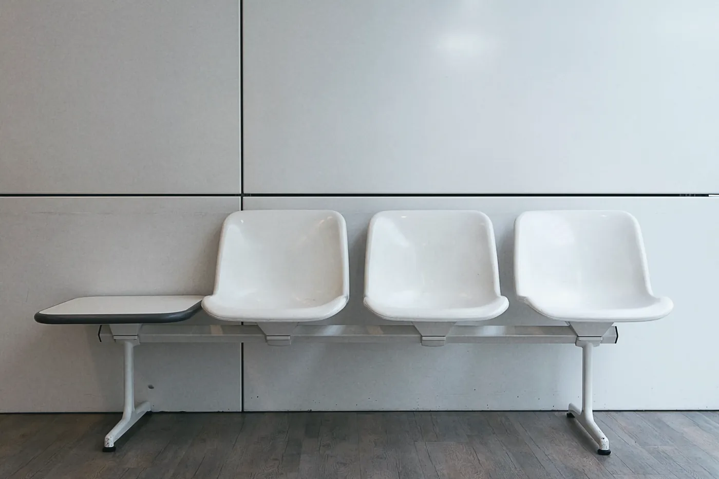A row of white waiting room chairs against a pale wall