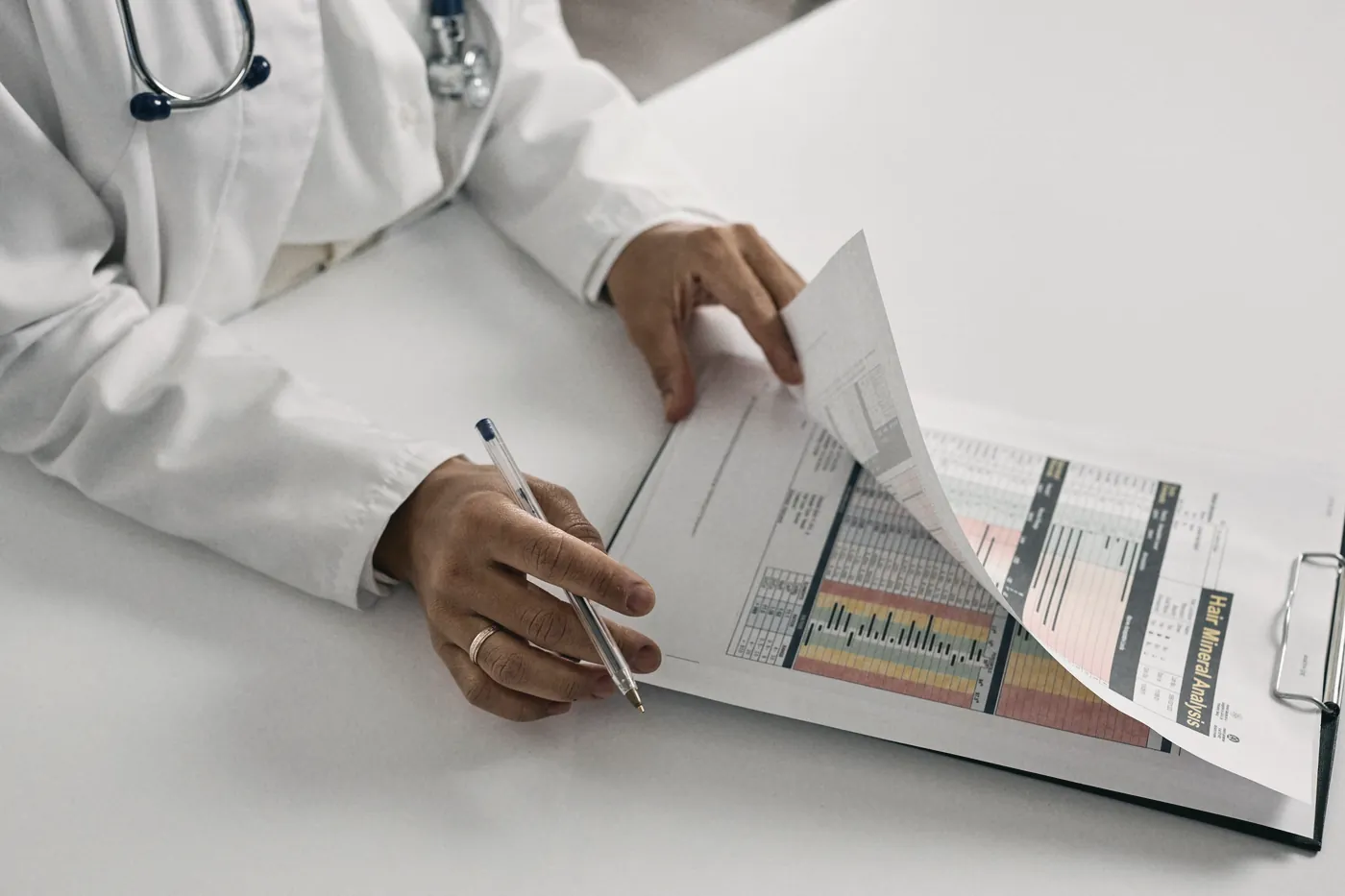 A clinician's hands holding a clipboard with medical forms