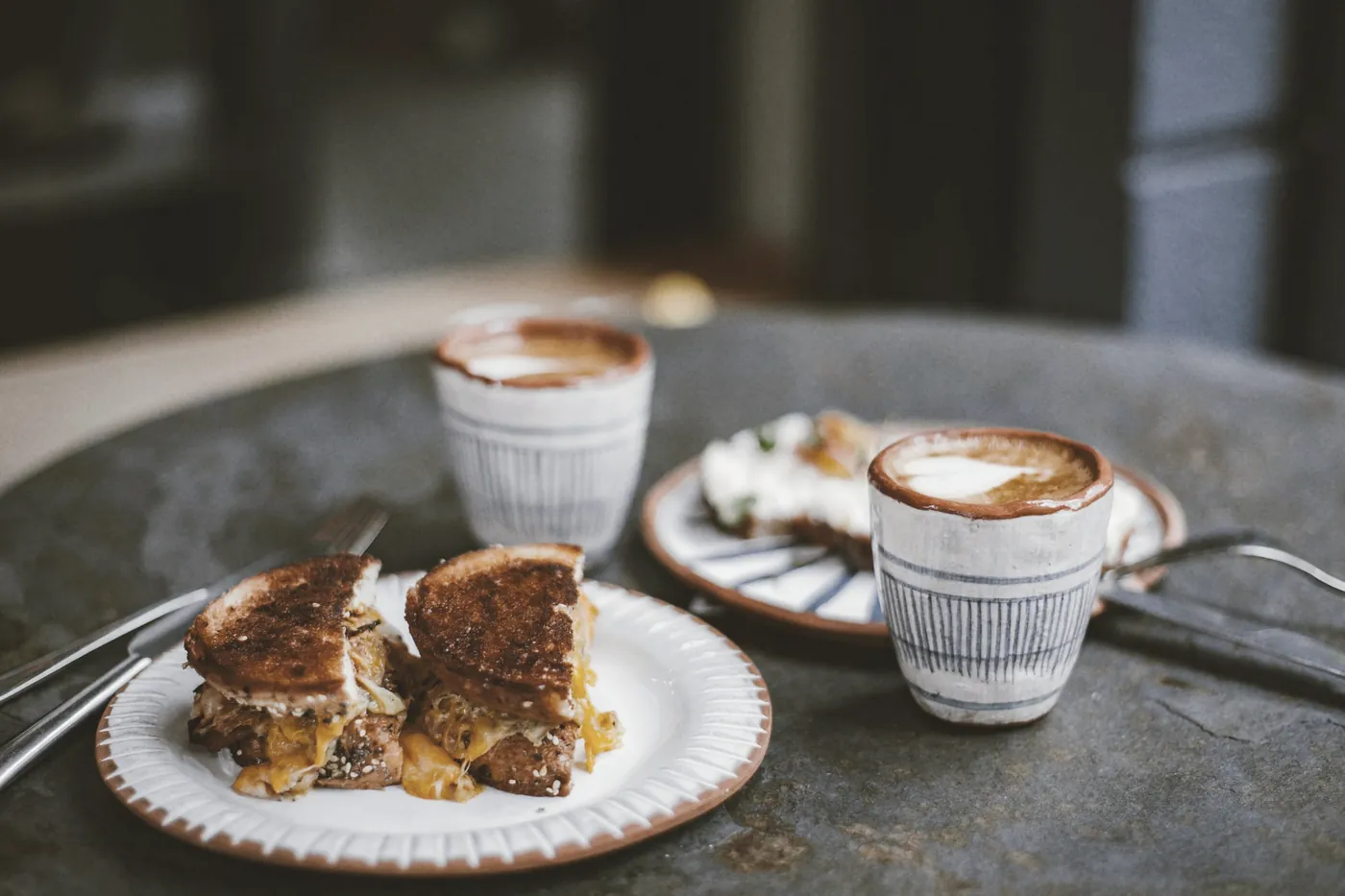 Coffee cups and a breakfast plate on a round cafe table