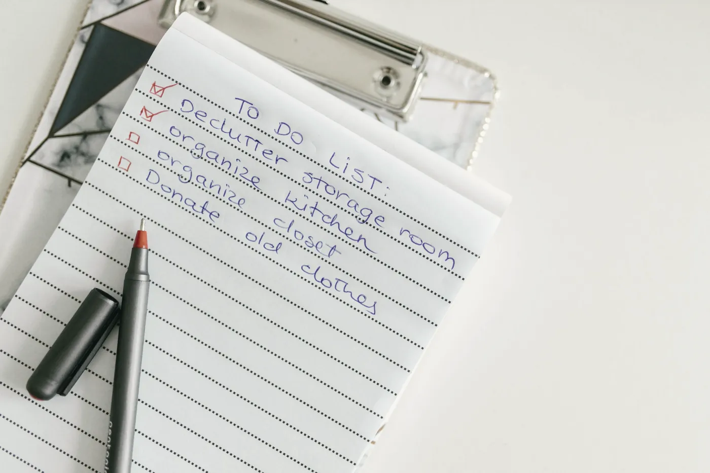 A notepad with a handwritten checklist and a pen on a white desk