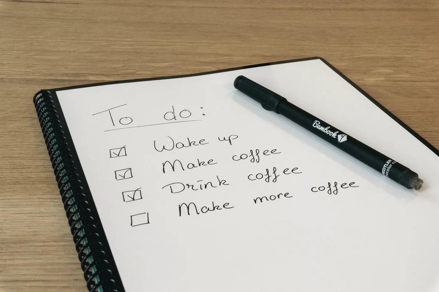 A handwritten to-do list in a notebook with a pen